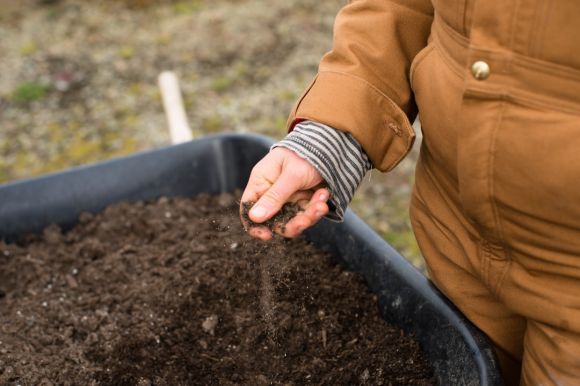 Soil - person in yellow jacket holding black soil